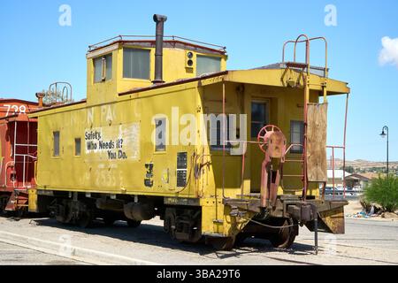 Barstow, Kalifornien, USA. Mai 2025. Fotografiert im Western America Railroad Museum in Barstow, trägt dieser verwitterte gelbe Caboose'`Union Pacific No. 25599''`seine Geschichte und seine Philosophie auf der Seite: 'Sicherheit'. Wer braucht es? Sie tun es.'' einst rollendes Büro und Aussichtspunkt für Zugpersonal, diente dieser Caboose Mitte des 20. Jahrhunderts am Ende der Union Pacific Güterzüge. Mit seinen Aussichtspunkten aus Kuppeln, Stahlleitern und dem roten Handbremsrad steht er heute als Relikt einer Zeit, bevor die hintere Telemetrie das menschliche Element ersetzte. Die verblassten Buchstaben Stockfoto